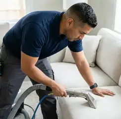 Professional upholstery cleaning technician using an extraction wand to deep-clean a fabric sofa, Tampa, FL.