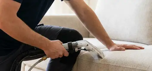 Professional upholstery cleaner deep-cleaning a fabric sofa with a handheld extraction tool, Tampa, FL.